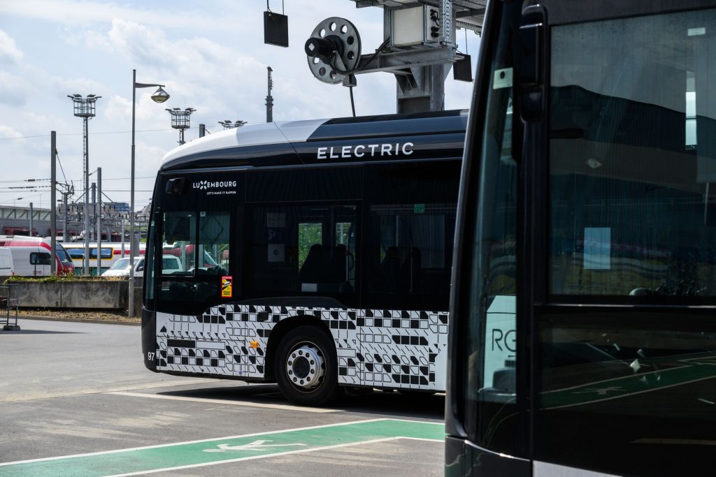 Photographie de deux bus électriques CFL. La partie avant d’un des deux bus est visible à l’avant-plan et le second, à l’arrière-plan, est sur le départ. Les bus présentent une livrée noire et blanche.