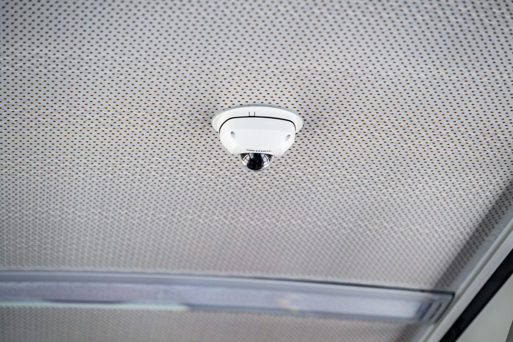 Foto einer Überwachungskamera an der Decke des Busses. Die Kamera ist weiß.